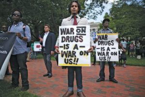 Black man at protest with sign that reads, "war on drugs is a war on us."